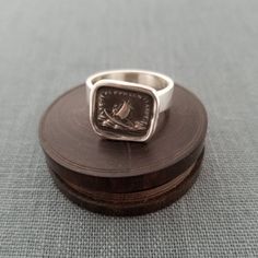 a silver ring sitting on top of a wooden box next to a piece of cloth