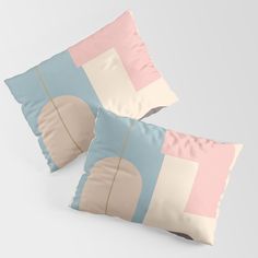 two decorative pillows with an abstract design on one pillow and the other in pink, blue, beige and white