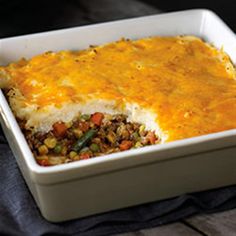 a casserole dish with meat and vegetables in it sitting on a black cloth