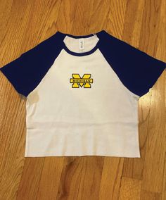 Cropped contrast sleeve baseball tee with Michigan patch White/navy tee Model wearing size XS Size down for a tight fit Blue Baseball Collar Top For Game Day, Blue Varsity Top With Baseball Collar, Blue Cotton Sporty Baseball Jersey, Sporty Blue Cotton Baseball Jersey, Sporty College T-shirt With Baseball Collar, Blue Cotton Tops With Baseball Collar, College Style Cotton T-shirt For Sports, Casual Cotton T-shirt With Contrast Panels, Casual Blue Baseball Jersey