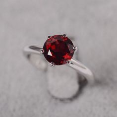 a close up of a ring with a red stone in it on a gray surface