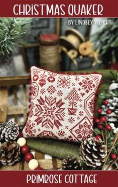 a red and white pillow sitting on top of a wooden bench next to pine cones