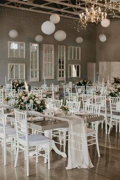 the tables and chairs are set up for a wedding reception in an old building with chandeliers hanging from the ceiling