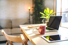 a laptop computer sitting on top of a wooden table next to a cup of coffee