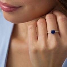 a close up of a person wearing a ring with an oval shaped blue stone on it