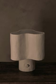 a white vase sitting on top of a wooden table