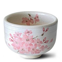 a white bowl with pink flowers painted on the outside and inside, in front of a white background