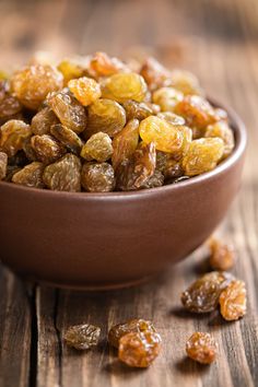 a bowl filled with raisins on top of a wooden table