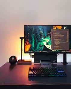 a computer monitor and keyboard sitting on a desk with a light up mouse next to it