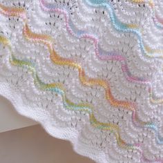 a white crocheted blanket with rainbows on it