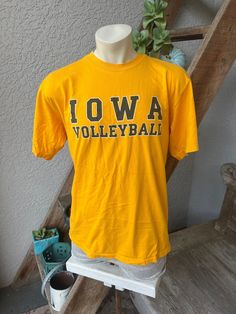 "GO HAWKEYES! This soft, heavyweight, Iowa gold, genuine 1990s vintage tee shirt is excellent condition. Made in the USA by Cotton Exchange -100% cotton. Check the measurements: SIZE: Pit to Pit: 21.5\" Collar to hem: 27.5\" Sleeves: 9.5\" shoulder to cuff. The tag says XL.  Check the measurements. The mannequin would be 5'10\" 170 lbs. ITEM" Vintage Sports T-shirt With Text Print, Casual Gold T-shirt With Logo Print, Vintage Gold Tops With Graphic Print, Vintage Gold Top With Graphic Print, Gold Vintage Tops With Graphic Print, Vintage T-shirt For Sports Season Fan Gear, Vintage Fan Gear T-shirt For Sports Season, Gold Short Sleeve T-shirt With Text Print, Vintage Gold Crew Neck Top