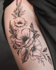 a woman's thigh with flowers and leaves tattoo on her leg, in black and white