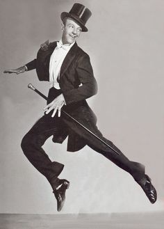 a man in a suit and top hat is jumping with his legs spread out to the side