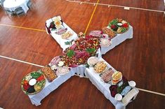 a cross made out of food sitting on top of a wooden floor next to tables