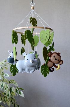 an animal mobile hanging from the ceiling next to a potted plant with leaves on it