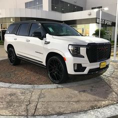 a white suv is parked in front of a building with black wheels and rims