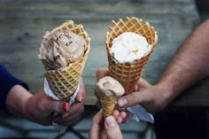 two people holding ice cream cones in their hands