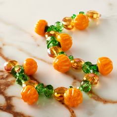 an orange and green beaded necklace on a marble surface