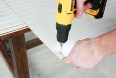 a person using a screwdriver to attach a piece of paper on top of a table