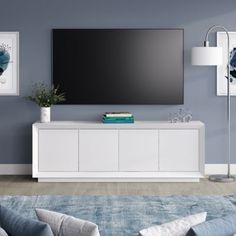 a large flat screen tv mounted to the side of a white entertainment center in a living room