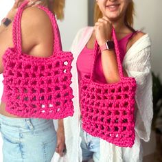 two women are holding pink crocheted bags