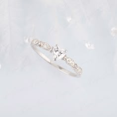 a diamond ring on top of a white background with feathers in the air behind it