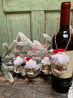 a bottle of wine sitting next to some ornaments and a corkscrew with santa's hats on it