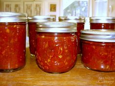 several jars filled with red sauce sitting on top of a wooden table