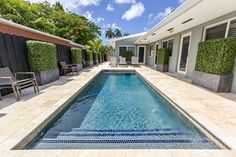 an outdoor swimming pool surrounded by lounge chairs and greenery on either side of it