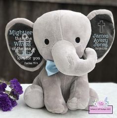 an elephant stuffed animal sitting next to a purple flower