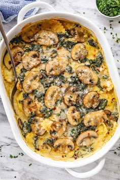 a casserole dish with mushrooms and spinach in it on a marble surface