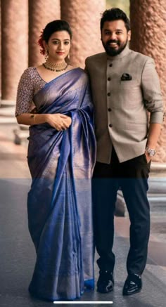 a man and woman standing next to each other in front of some pillars with columns