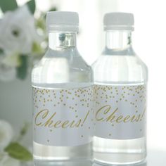 two water bottles sitting next to each other on a table with flowers in the background