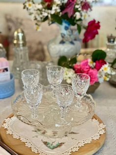 a table topped with lots of glassware on top of a wooden plate