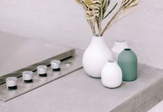 three white vases sitting on top of a counter