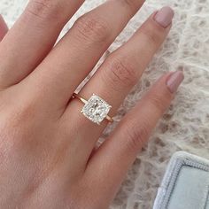 a woman's hand with a diamond ring on top of her finger and an engagement band