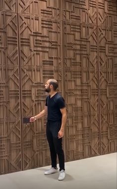 a man standing in front of a wooden wall