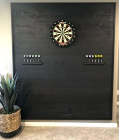 a dart board mounted to the side of a wall next to a potted plant