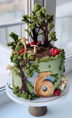 a cake decorated with trees and mushrooms on a table next to a window sill