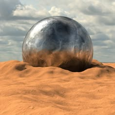 a large metal ball sitting in the middle of sand