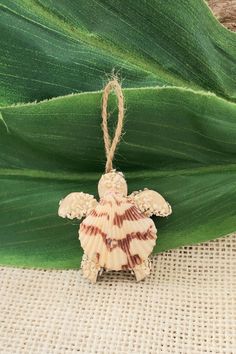 a shell angel ornament hanging on a green leaf