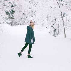 a woman is walking through the snow with her hat on and boots in front of her