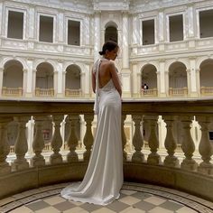 a woman in a white dress is looking down at the floor and balcony outside an ornate building