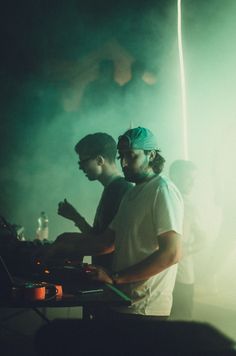 two men standing next to each other in front of a dj's turntable