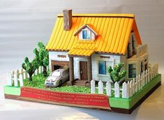 a toy house with a car parked in front of it on a table next to a white fence