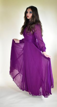 "Stunning statement dress in purple silk by Elka couture sized as a 38\" .  Perfect for an alternative wedding dress or simply to standout at an event. Team with high black heels for WOW factor. The acetate lining is cut quite narrow but the over chiffon is generous giving a swirl to the skirt when moved.  The dress has a Sweetheart bodice lining overlaid with chiffon that fits high on the neck. Sheer long sleeves complete the look of this Vampire bride dress. Note it comes with two separate len Purple Maxi Dress For Party, Purple Fitted Long Sleeve Gown, Fitted Long Sleeve Purple Gown, Purple Maxi Dress For Prom, Fitted Purple Maxi Dress For Evening, Purple Long Sleeve Gown For Prom Season, Purple Maxi Gown For Prom, Purple Evening Dress For Fall, Purple Maxi Dress For Prom Season