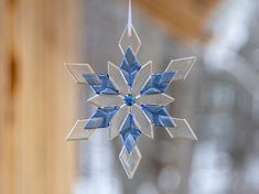 a snowflake ornament hanging from a string in front of a window