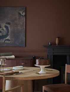 a dining room table with two wine glasses on it and a painting hanging above the table