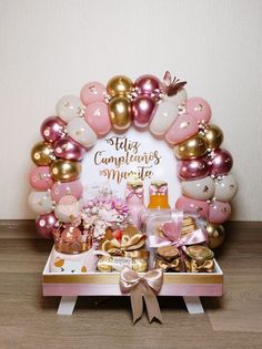 a table topped with lots of pink and gold balloons next to a sign that says hello congratulations