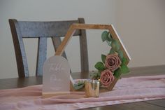 a wooden table topped with a vase filled with flowers and a sign that says take one